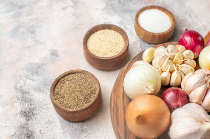 Spices and herbs in wooden bowls on a textured surface